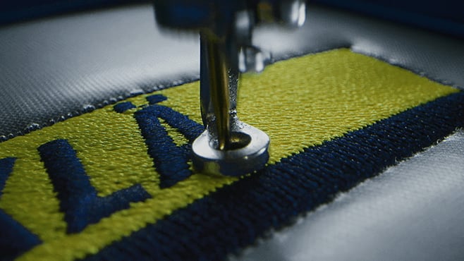 Machine à broder qui brode un logo sur un vêtement de travail